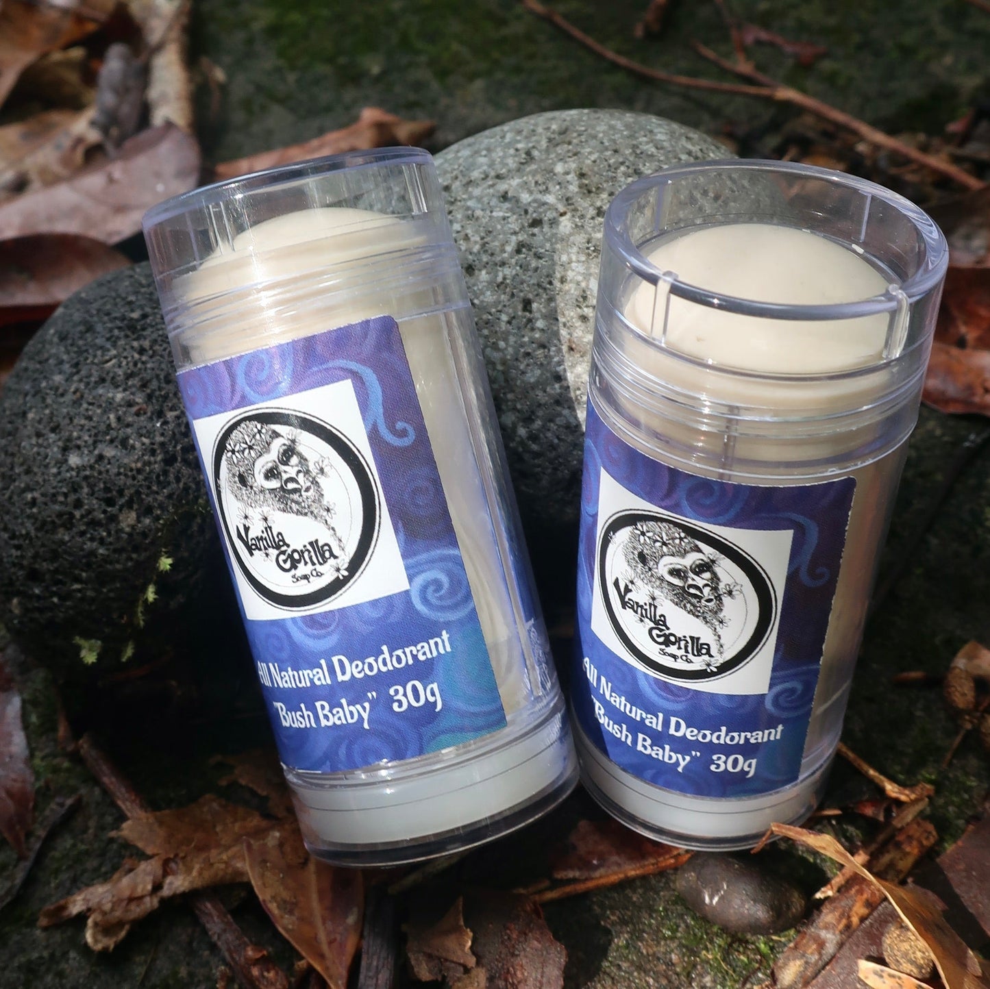Two containers of 'Vanilla Gorilla' Bush Baby natural deodorant on a natural background with leaves and stones.