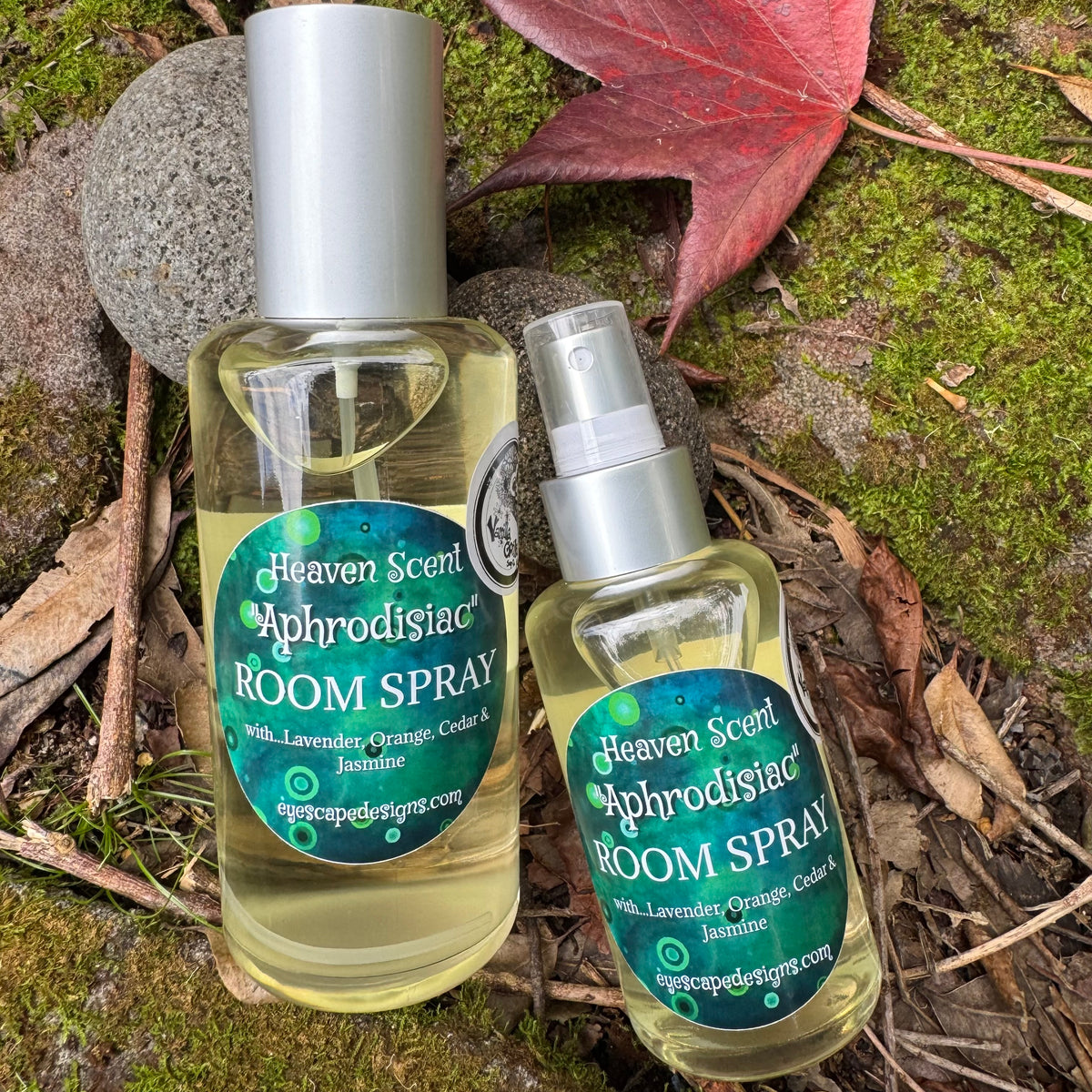 Two bottles of Heaven Scent Aphrodisiac Room Spray on a natural background with leaves and moss.