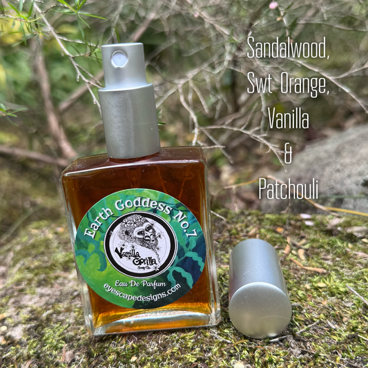 A square glass Eau De Parfum bottle filled with amber liquid, shown outdoors on mossy ground with its silver cap removed and placed beside it. The label reads 'Earth Goddess No.7 