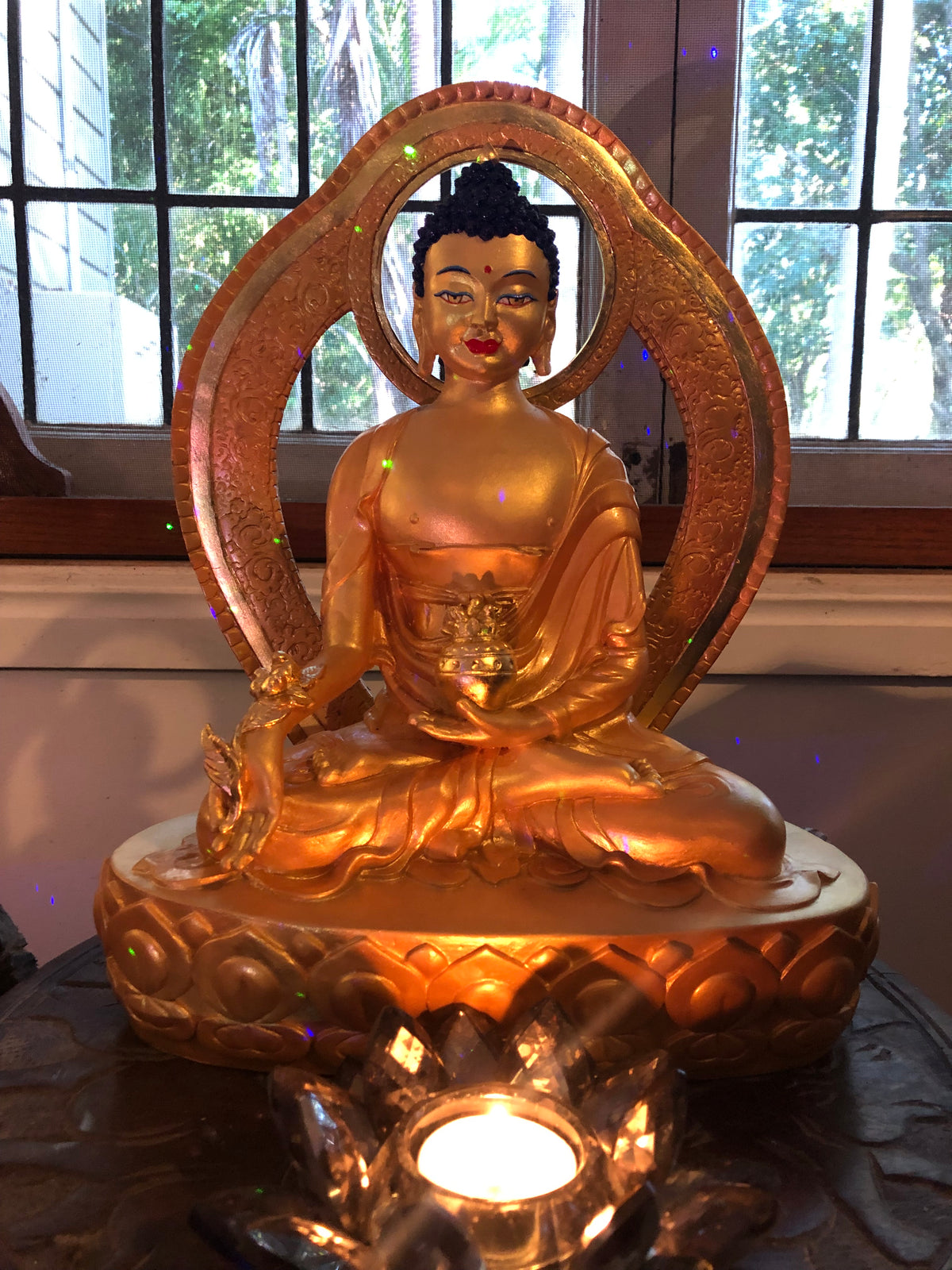 Medicine Buddha statue finished in 24ct gold leaf with lotus candle in front 