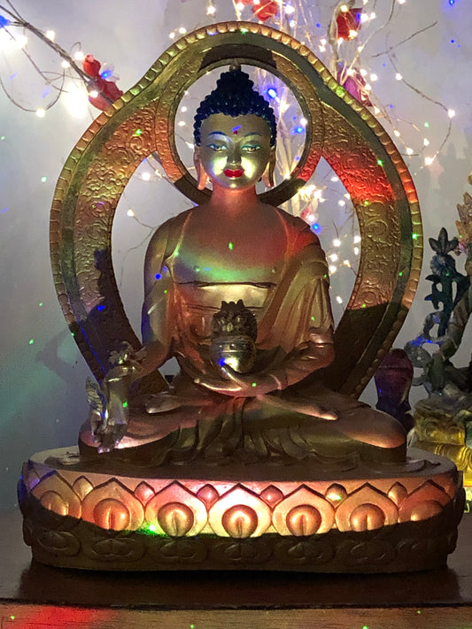 Medicine Buddha Statue in gold with laser lights and fairy lights behind