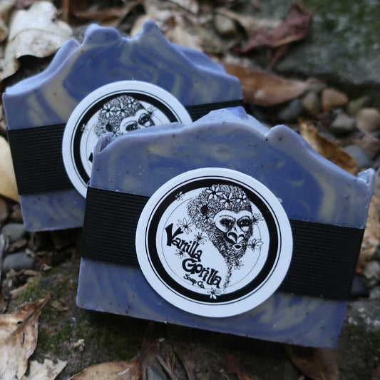 Two blue Lavender soap bars w/black bands & a Vanilla Gorilla logo on a leafy ground