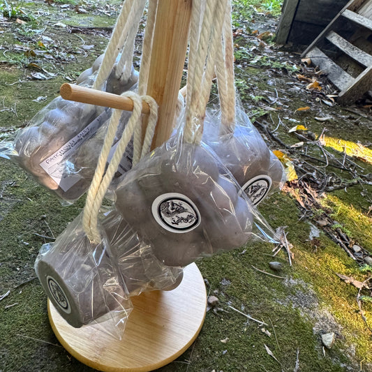 Purple soap on a ropes on a wooden stand with cello wrap, outdoors.