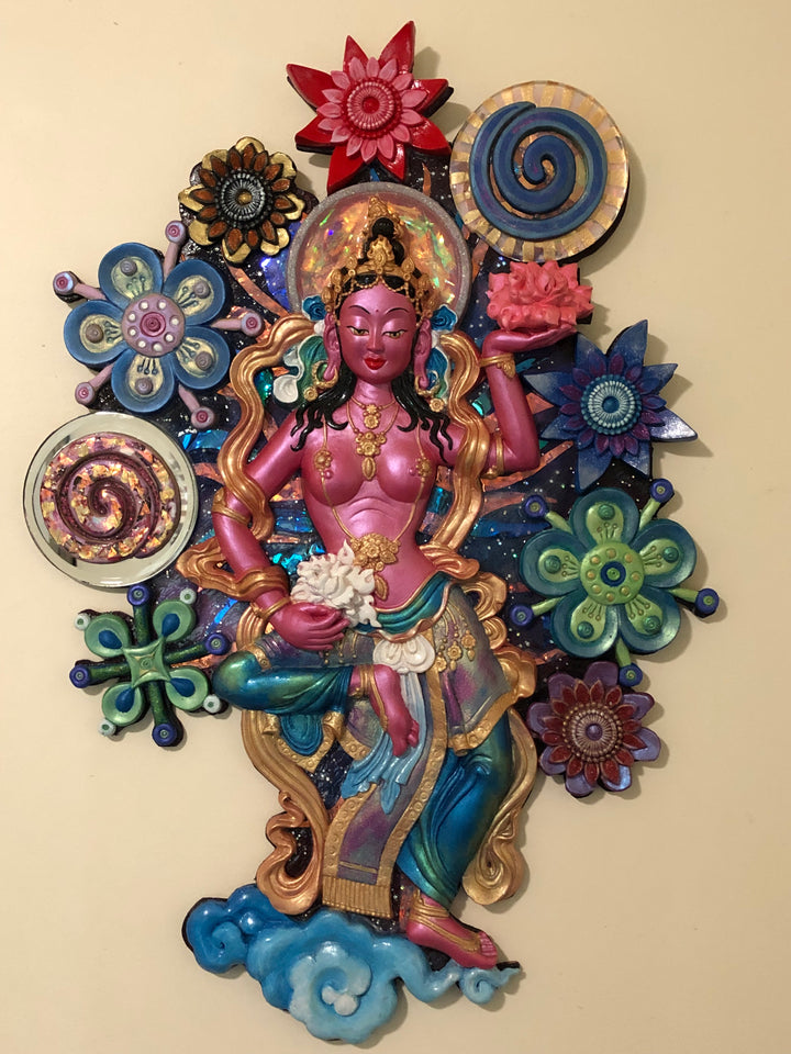 A colorful wall hanging artwork featuring a pink offering goddess figure amidst a bed of flowers with spiral patterns in a sparkling galaxy background.