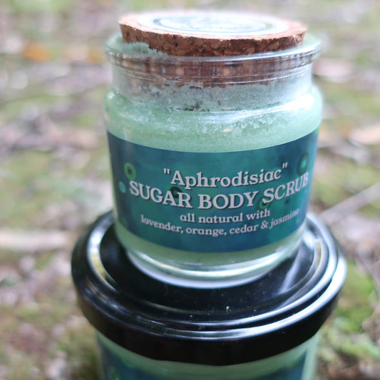 Green jar of sugar body scrub with a black lid on a natural background