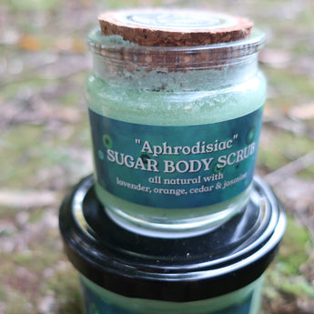 Green jar of sugar body scrub with a black lid on a natural background