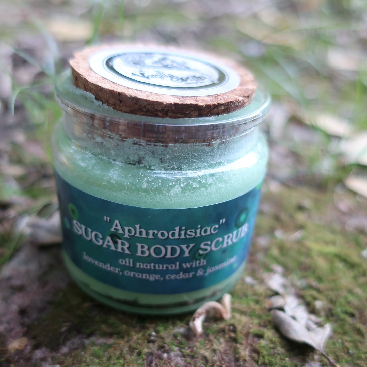 Jar of Aphrodisiac sugar body scrub on a mossy surface