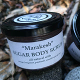 Two jars of 'Marakesh' Sugar Body Scrub with visible branding on a natural background.