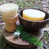 Coconut soap in a wooden bowl with a brush on a natural background