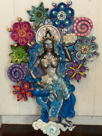 silver offering goddess sculpture in a sea of colourful semi abstract flowers
