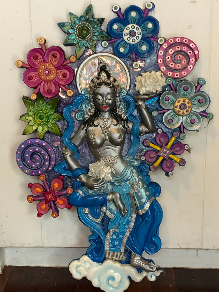 silver offering goddess sculpture in a sea of colourful semi abstract flowers
