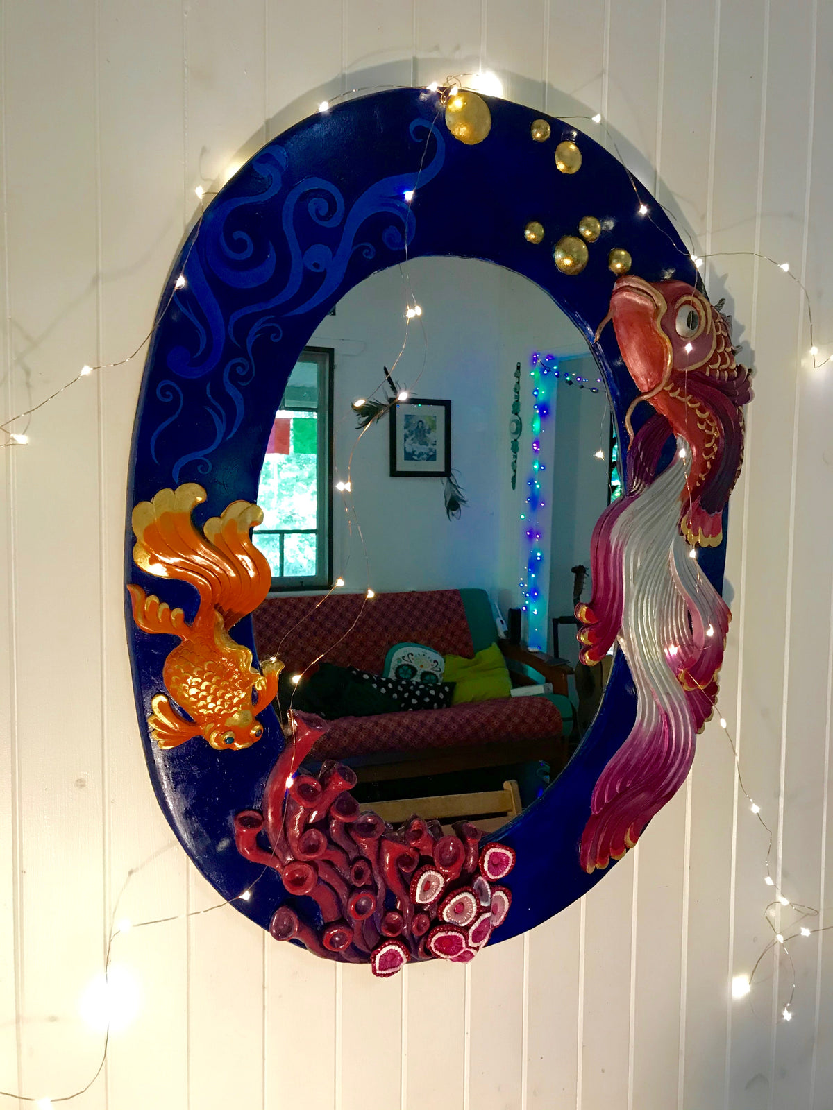 Large oval mirror with sculpted fish and coral painted in blue, pink and gold