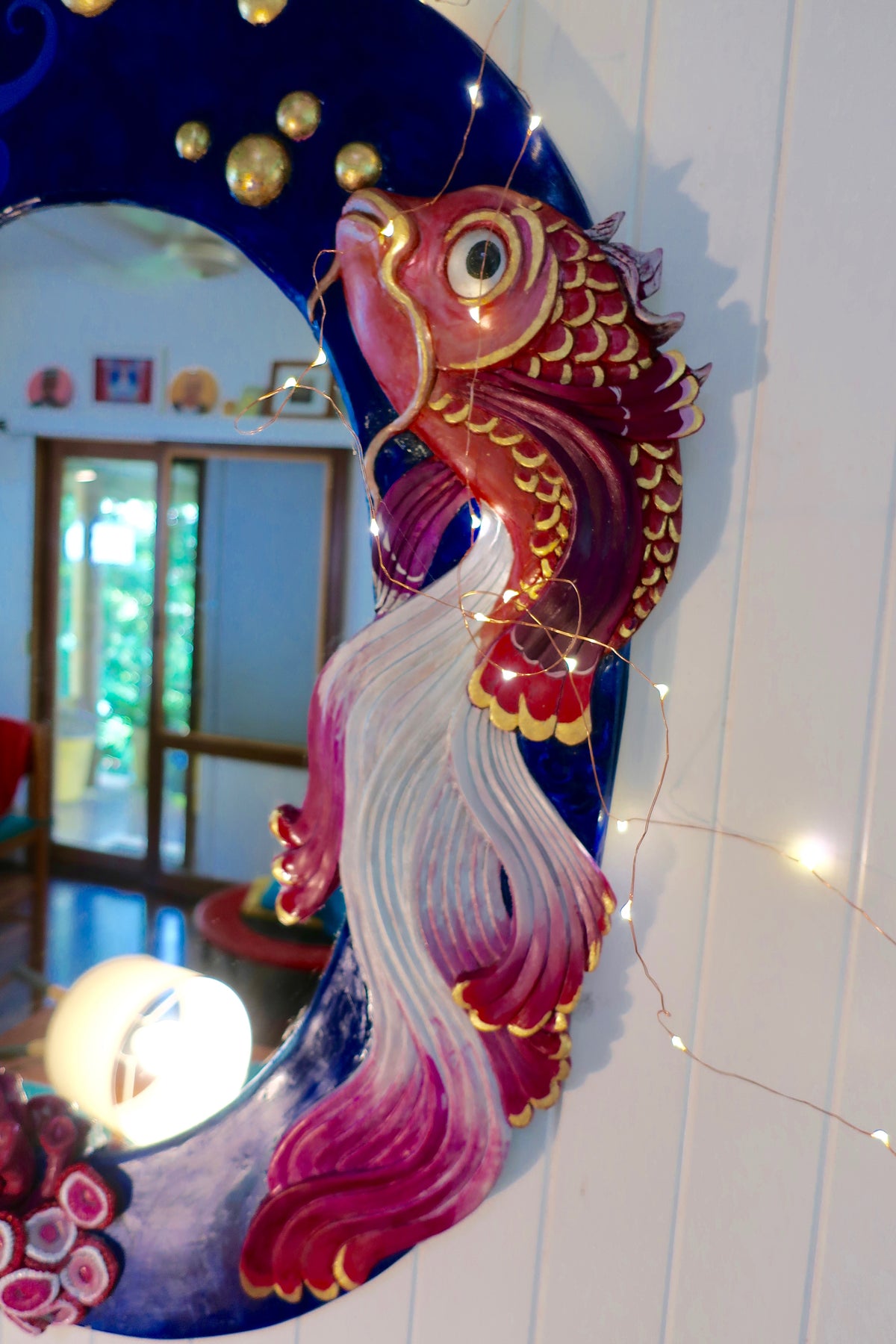 Close up of half the large oval mirror with large sculpted gold fish