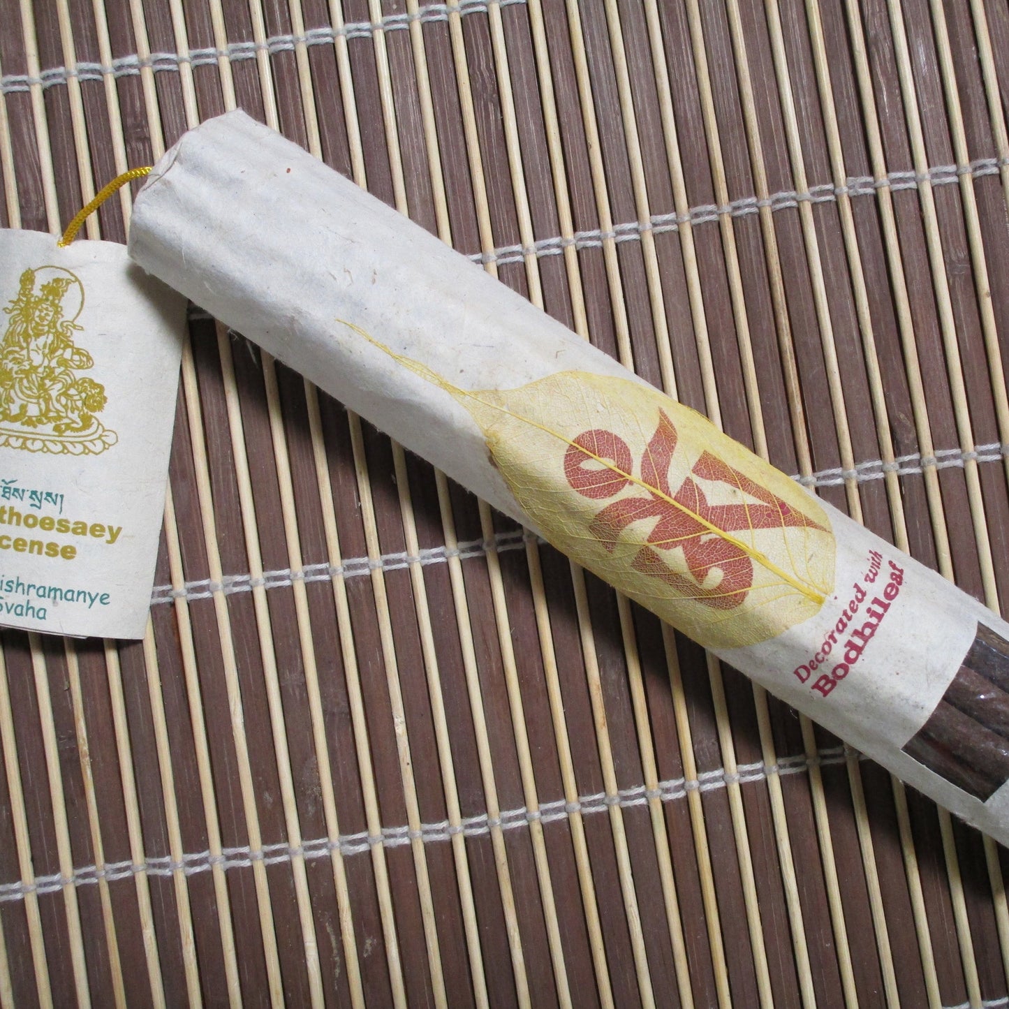 A pack of Namthoesaey incense with a few sticks visible outside the packaging, which is predominantly gold and yellow with text.